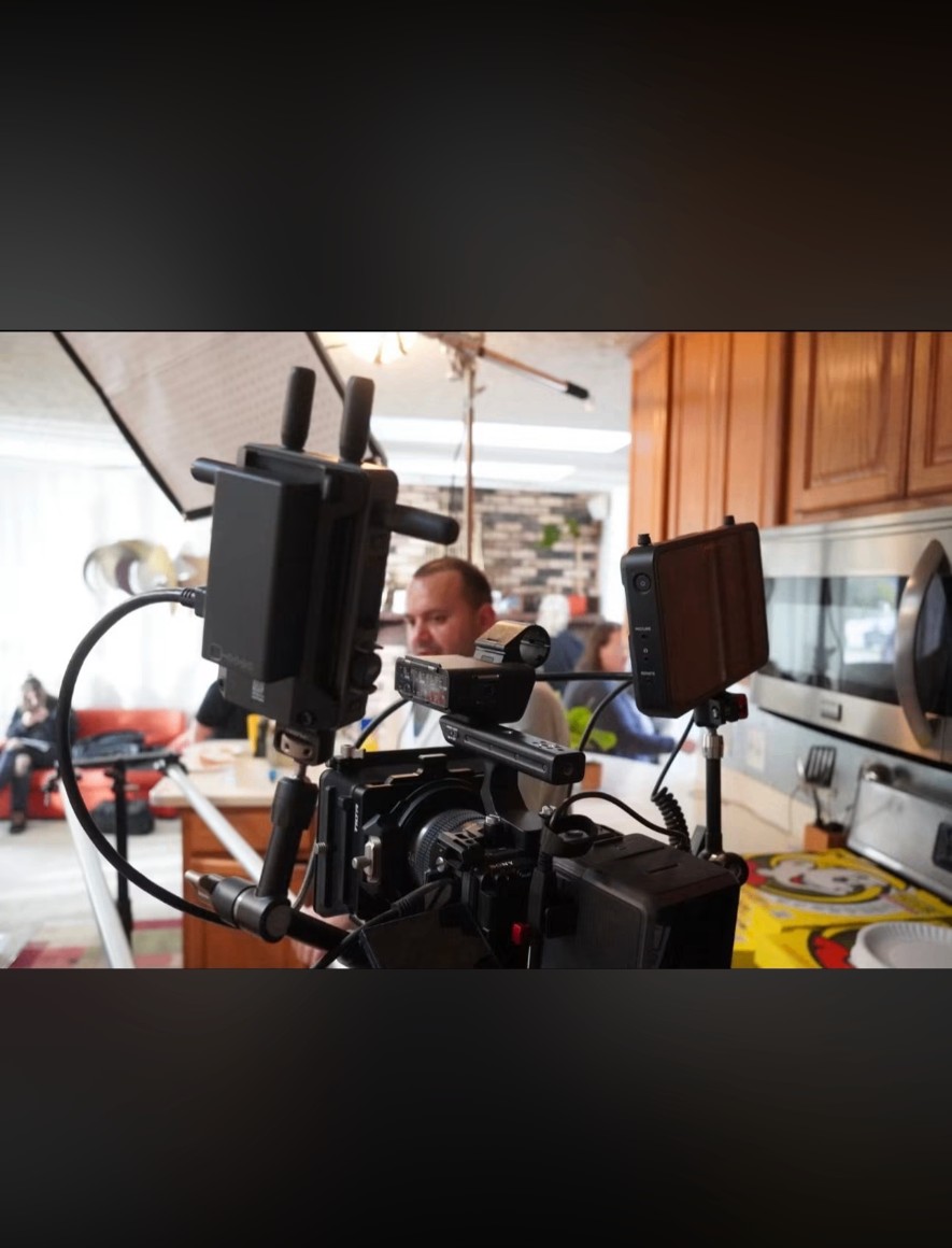 Cinema camera rig with monitors framing a subject in a kitchen