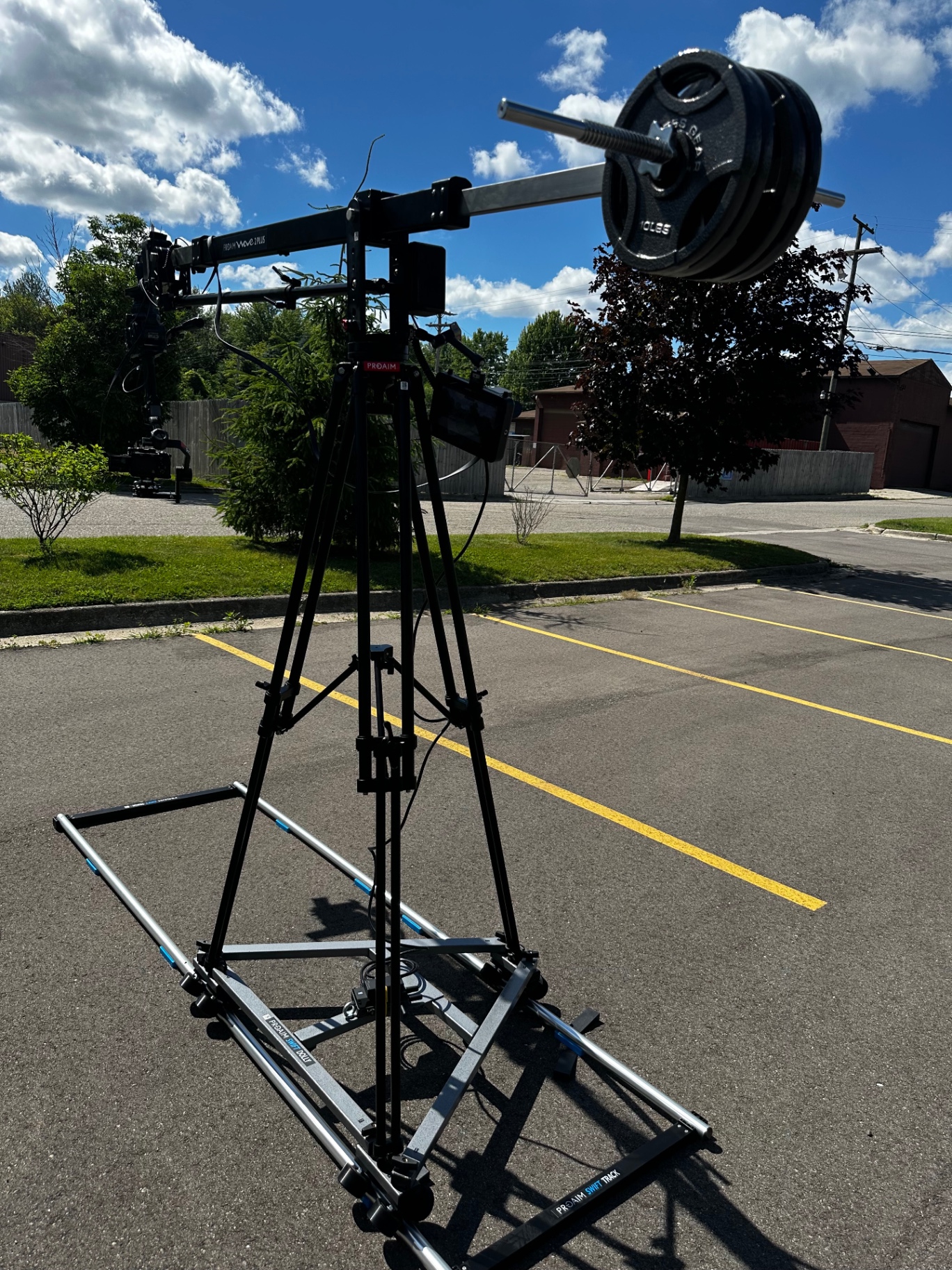 Counterweighted jib arm and slider rig set up in a parking lot under blue sky